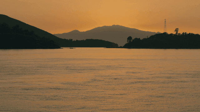 Sunset over a calm sea with distant hills
