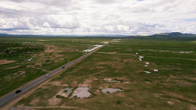 Cars Driving on a Road in a Vast and Treeless Grassland