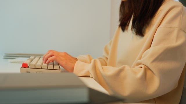 Woman using a keyboard at a desk in a calmly lit room