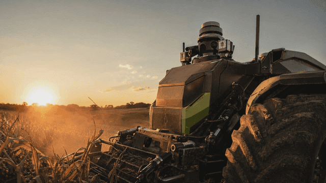 Future unmanned tractor in field at sunset