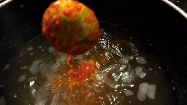 Adding red seasoning to a pot with broth