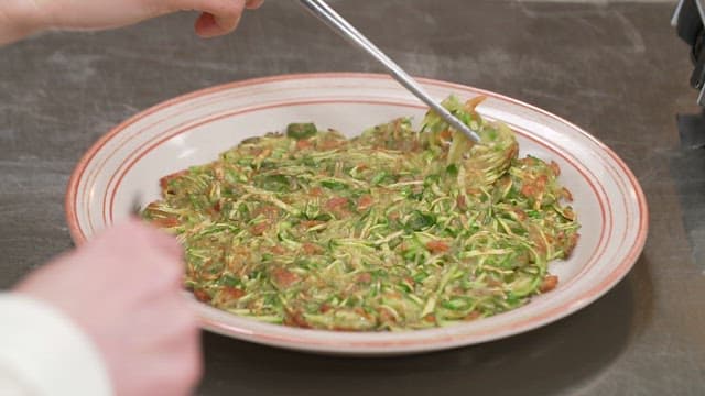 접시에 담긴 애호박전을 젓가락으로 집는 모습