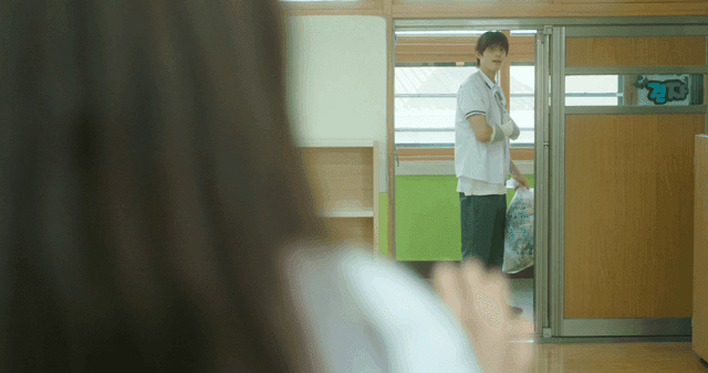 Student carrying trash in a classroom