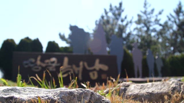 Sign indicating Haenam Ttangkkeut Village between the grass and trees