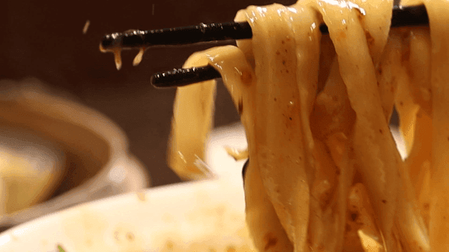 Spicy hand-cut noodles picked up with chopsticks