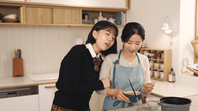 Daughter tasting soup her mother cooked in cozy kitchen.