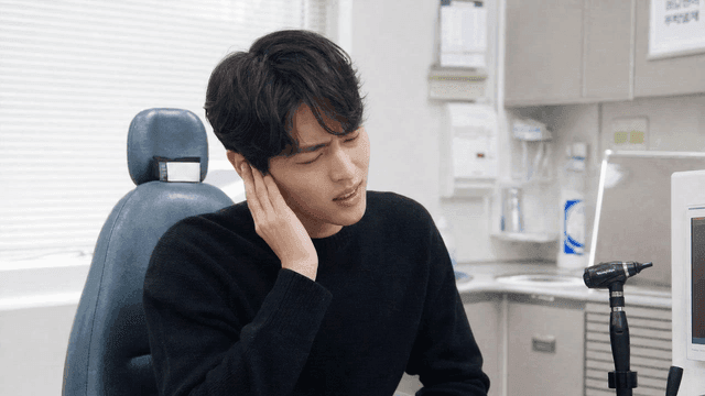 Man holding his ear in discomfort at a clinic