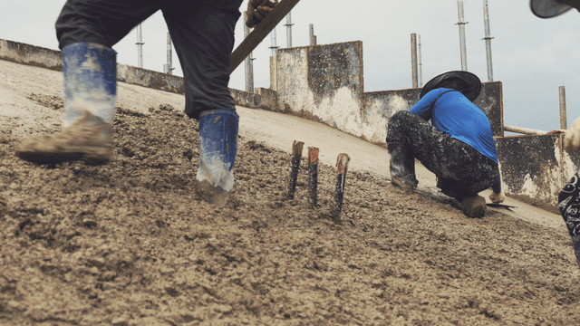 경사면에서 젖은 콘크리트를 다듬는 작업자들