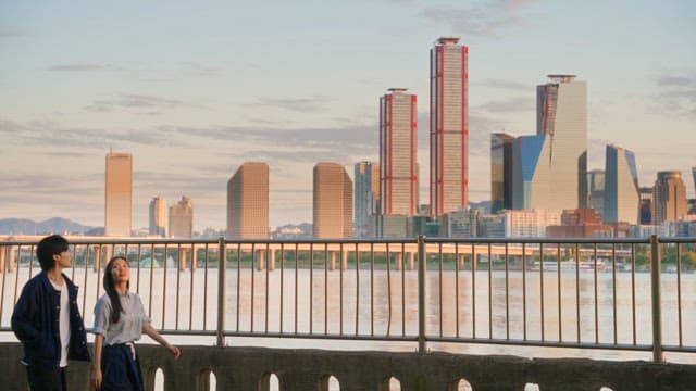 도시 풍경을 배경으로 강변을 걷는 커플