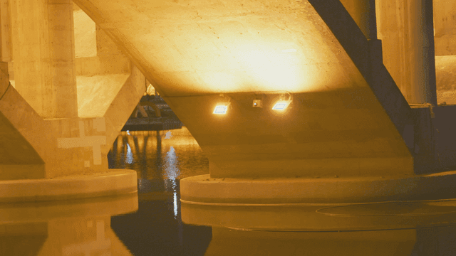 Night river under illuminated bridge structure
