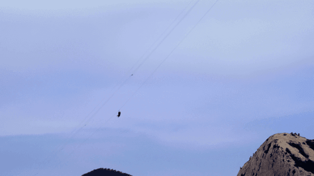 산악 지형 위로 집라인을 타는 사람