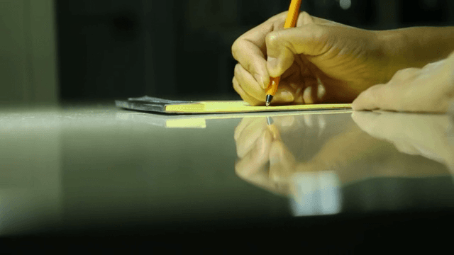 펜으로 메모장에 글을 쓰는 손