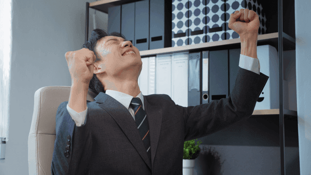 책상에 앉아 환호하는 사업가