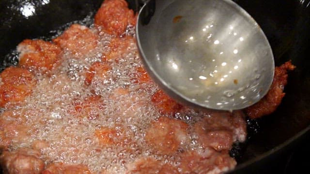 Frying meatballs in hot oil with a ladle