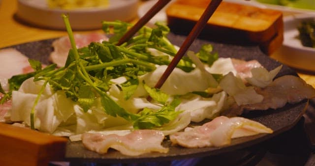 불판 위에서 미나리 양배추와 맛있게 구워지는 삼겹살