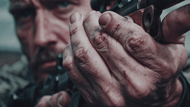 A focused man aiming with a rifle