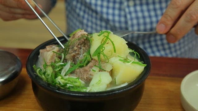 Braised pork backbone meat in clear soup picked up with chopsticks