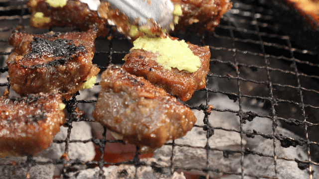 Garlic-marinated beef short ribs flipped with tongs