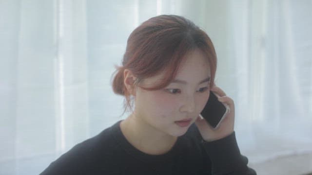 하얀 커튼이 있는 방에서 통화하는 여자