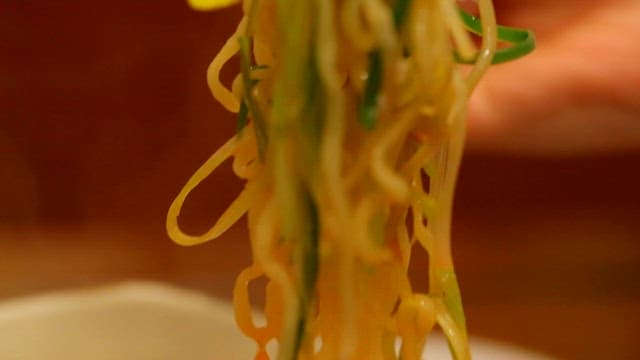 Ramyeon noodles being lifted with chopsticks