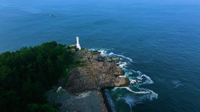 White Lighthouse on the Rocky Coast and Blue Sea