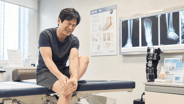 Male patient in pain, clutching his foot at clinic