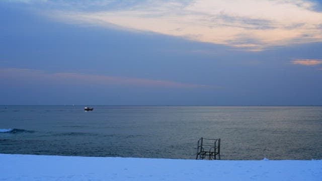 Boat passing through a calm sea under the evening sunset sky