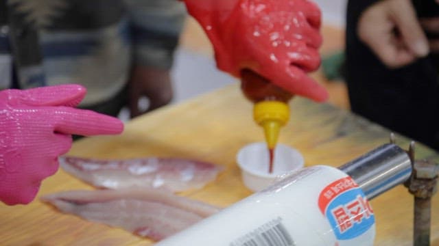 People Eating Freshly Prepared Raw Fish Dipped in Red Sauce