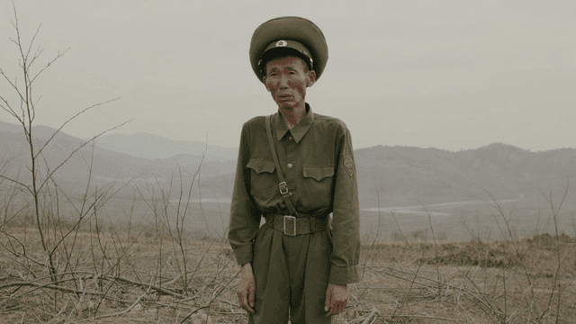 Emaciated North Korean soldier standing in desolate field