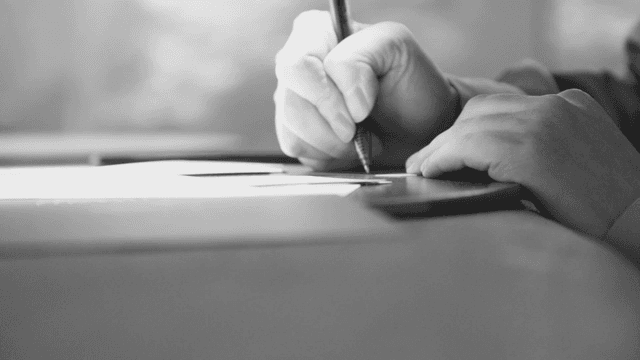 책상위에서 종이에 글을 쓰는 손