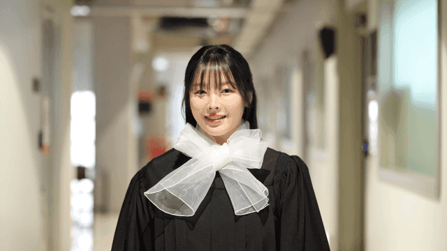 Graduate smiling in a hallway