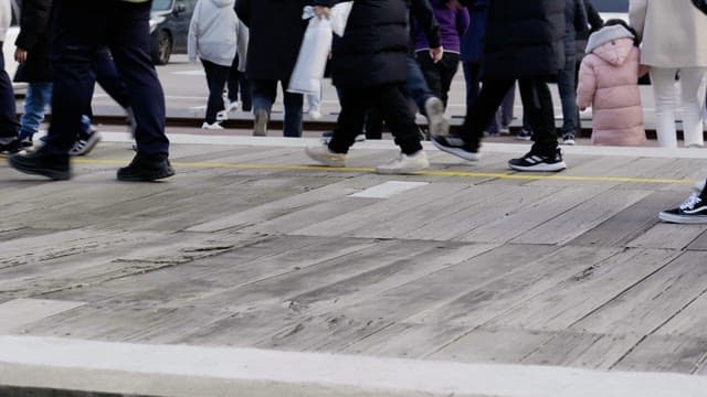 Legs of people walking on a wooden deck near the parking lot