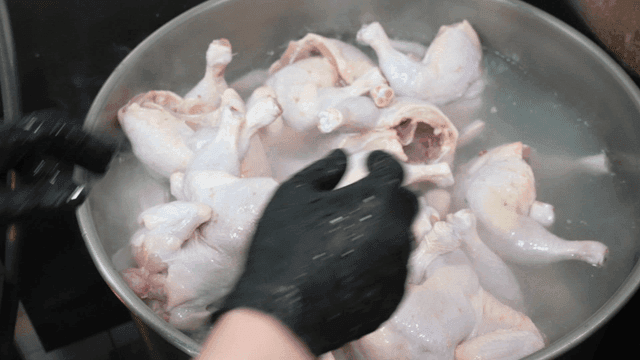 Raw chickens being put into large pot