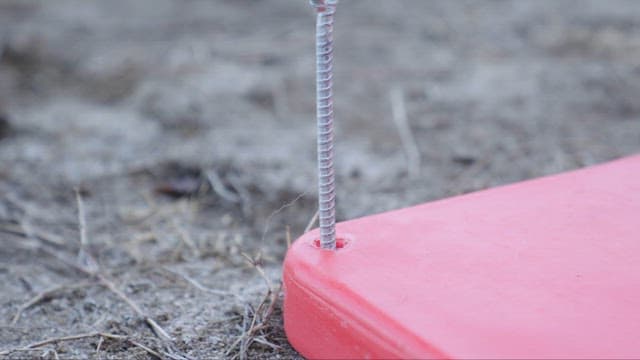 물체를 바닥에 고정시키기 위해 팩을 박고 있는 망치