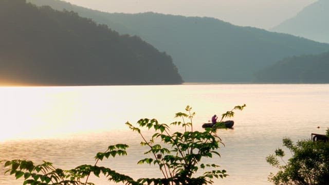 Fishing from a boat on a calm lake glowing in the sunlight