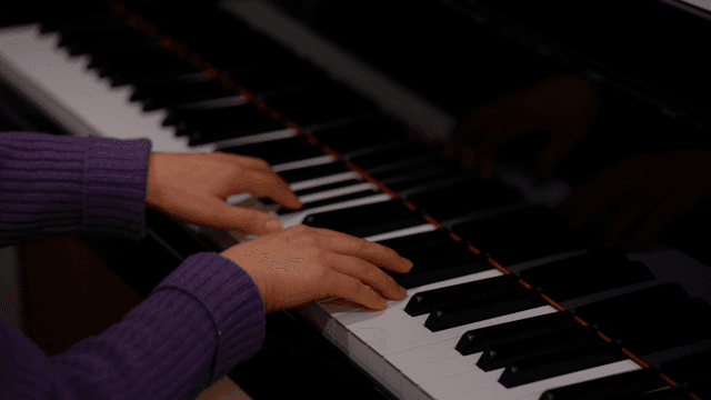 Hands playing piano keys indoors