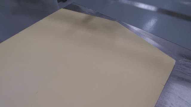 산업 주방 환경에서 자로 반죽을 정확하게 자르는 장갑 낀 작업자