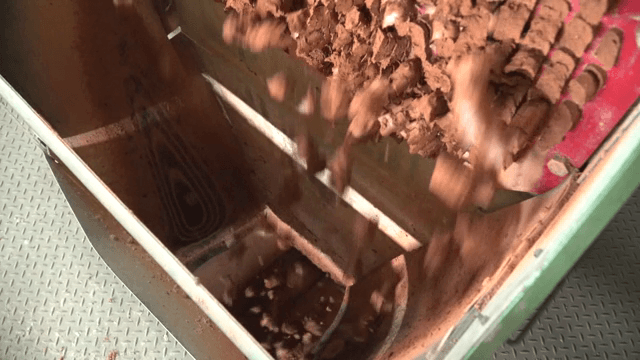 Brown clay being processed in a machine