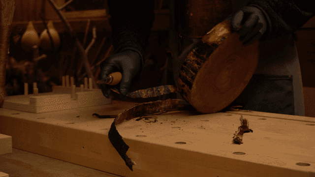 장인이 나무 조각의 껍질을 벗기는 모습