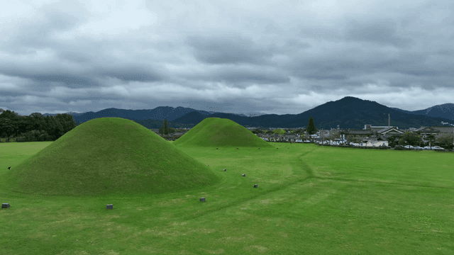 Green burial mounds under cloudy skies