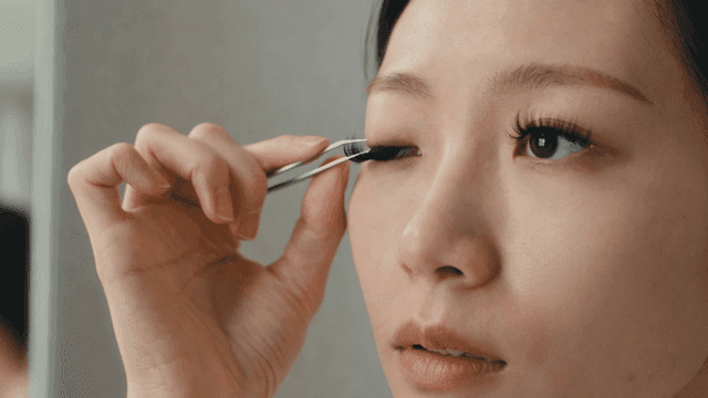 A woman applying false eyelashes