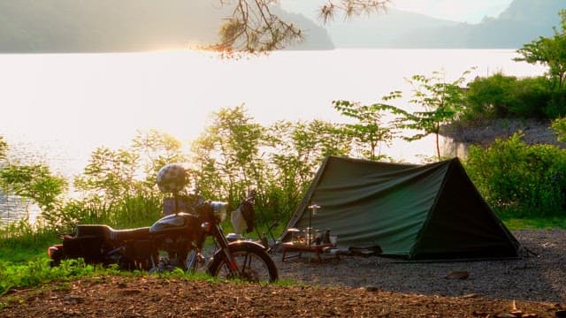 Early morning camping by the serene lakeside with tents and motorbikes