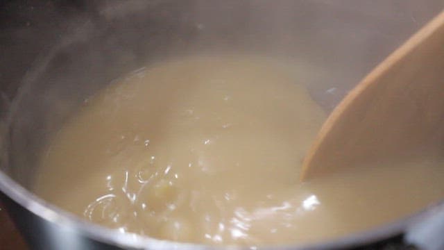 Stirring chestnut jam in a steaming pot with wooden spatula