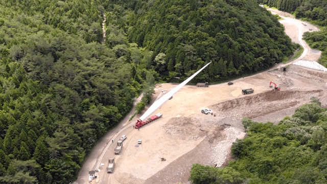 산 속 공사현장에서 풍력 터빈 자재를 운반하는 모습