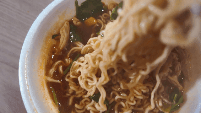 Chopsticks picking up steaming cup noodles