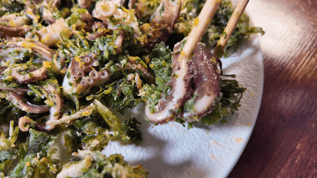 Fried vegetables topped with baby octopus on plate