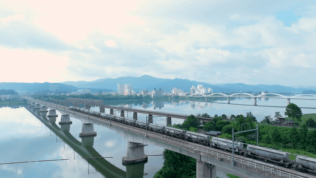 Train crossing a bridge over a calm river