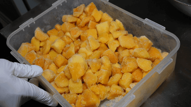 Frozen mango pieces in plastic container