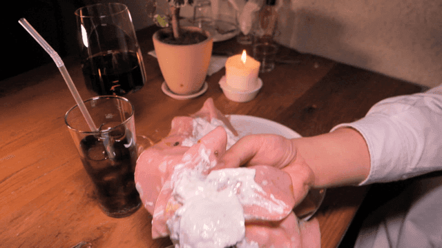 Hand holding mortadella pizza topped with cream