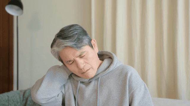 실내에서 목을 마사지하는 노인